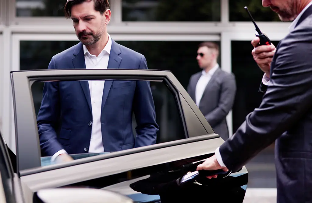 Sicherheitsmann öffnet Autotür für VIP